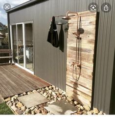 an outdoor shower in front of a building with rocks on the ground and a wooden deck