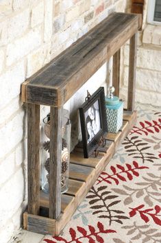 a wooden shelf with two pictures on it next to a brick wall and a rug