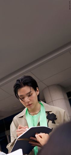 a woman holding a book in her hands and looking down at the paper she is reading