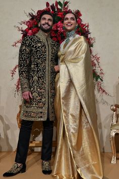 two people standing next to each other in front of flowers