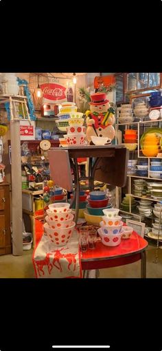 there are many bowls on the table in this shop and one is red, white, blue and orange