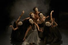 a group of people with masks on their faces posing in front of a black background