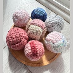 six crocheted donuts sitting on top of a wooden plate next to a window