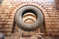 an old tire hanging from the side of a brick building, with bricks surrounding it