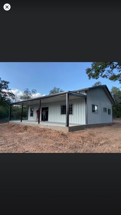 a mobile home with the door open on dirt ground next to trees and grass in front of it