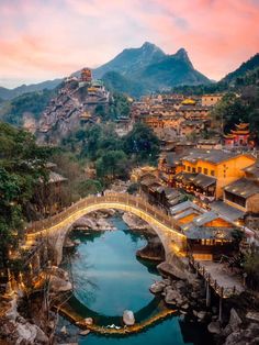 a bridge over a body of water with buildings on top of it and mountains in the background