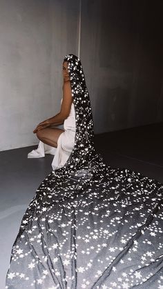 a woman sitting on top of a bed wearing a black and white dress with stars