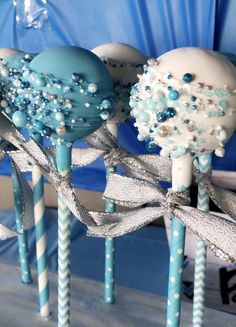 blue and white candy lollipops are on sticks with silver ribbons around them