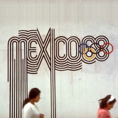 two women walking past the olympic logo