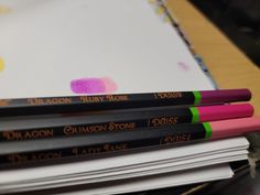 four pencils sitting on top of each other next to a pile of books and papers