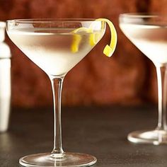 two martinis with lemon garnish sit on a table