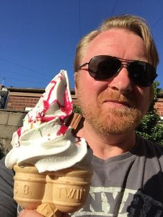 a man holding an ice cream cone with sprinkles on it and wearing sunglasses