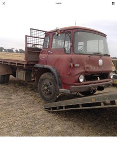 an old red truck parked in a field