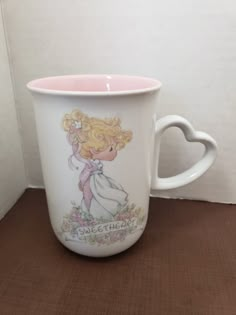 a white coffee cup with a blonde haired girl holding a flower in her hand and the words sweetheart on it