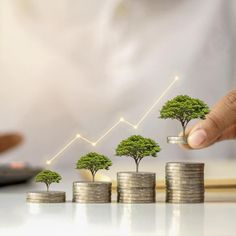 a hand is pushing coins with trees growing on them