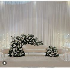 a wedding ceremony setup with white flowers and greenery in front of a curtained backdrop