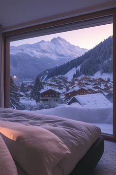 a bed sitting next to a window with a view of snow covered mountains in the background