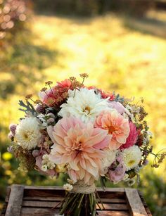 a bouquet of flowers sitting on top of a wooden crate in front of some grass