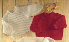 three knitted sweaters and shoes on a wooden floor