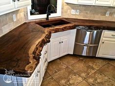 a wooden counter top in a kitchen with white cabinets and stainless steel dishwasher