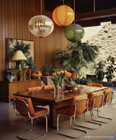 a dining room table surrounded by chairs and hanging lights over it's head area