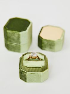 an engagement ring in a green velvet box with two matching rings on the inside one