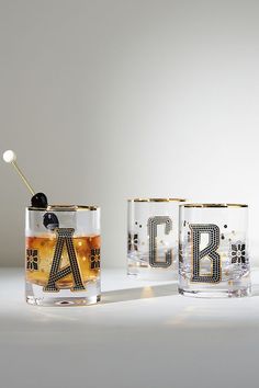 two glasses with letters and an object in the middle one has a black ball on it