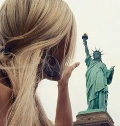 a woman with headphones is looking at the statue of liberty in new york city