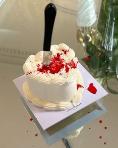 a cake with white frosting and red sprinkles on it sitting on a table