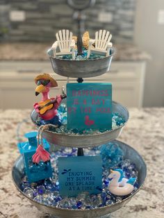 a three tiered tray with blue and white items on it that says happiness is a day at the pool