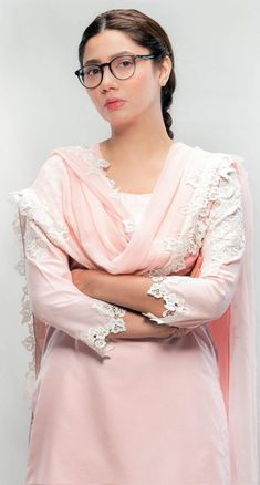 a woman wearing glasses and a pink dress standing with her arms crossed in front of her chest