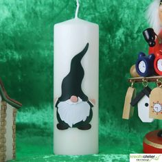 a candle with an image of a gnome on it next to a clock and other decorations