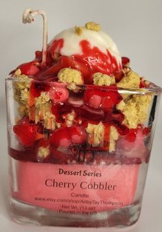 a dessert with cherries, crumbles and whipped cream on top in a glass container