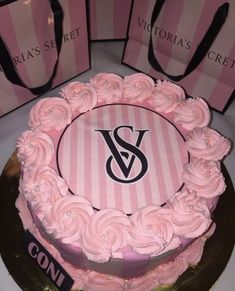 a pink cake sitting on top of a table next to two bags and a purse