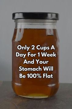 a glass jar filled with honey sitting on top of a table next to a sign that says, only 2 cups a day for 1 week and your stomach will be 100 % flat