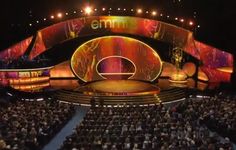 the stage for an award ceremony is lit up with bright lights and people are seated in rows