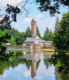 a large building sitting on top of a lake surrounded by trees