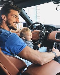 a man driving a car with a baby in his lap