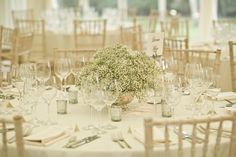 the table is set with glasses, silverware and baby's breath flower centerpiece