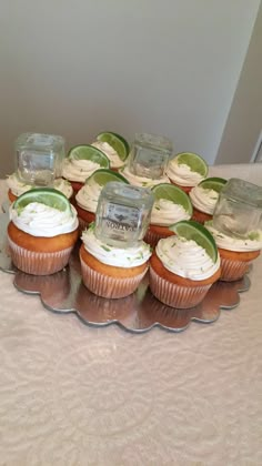 cupcakes with lime slices and frosting are arranged on a platter, ready to be served