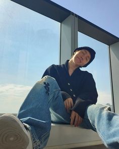 a woman sitting on top of a window sill next to a pair of jeans