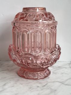 a pink glass vase sitting on top of a marble counter