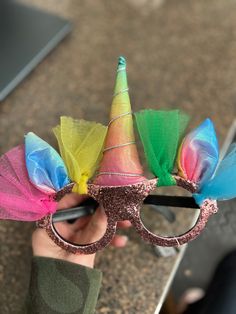 a person holding up a pair of glasses with colorful hair accessories on top of it