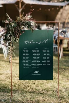 a sign that is sitting in the grass next to a table with flowers on it