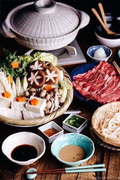 an assortment of food on a table with chopsticks and other foods in bowls