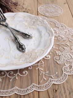 there are two forks on the plate with lace doily next to it, and one fork is in the middle of the plate