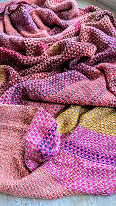 colorful knitted blankets are laying on the floor