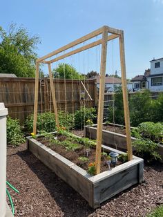 an outdoor vegetable garden with raised wooden planters and trelliss on the sides