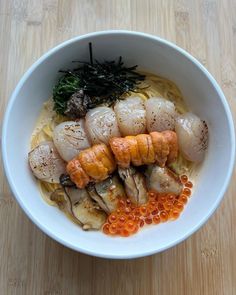 a white bowl filled with food on top of a wooden table next to chopsticks