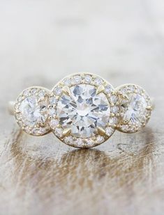 three stone engagement ring with diamonds in the center on a wooden surface, close up